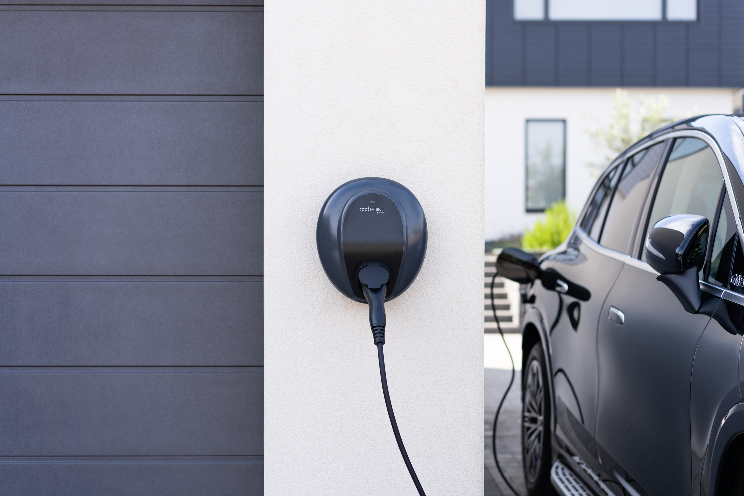 Mercedes electric SUV charging at a Pod EV home charger outside a modern home.