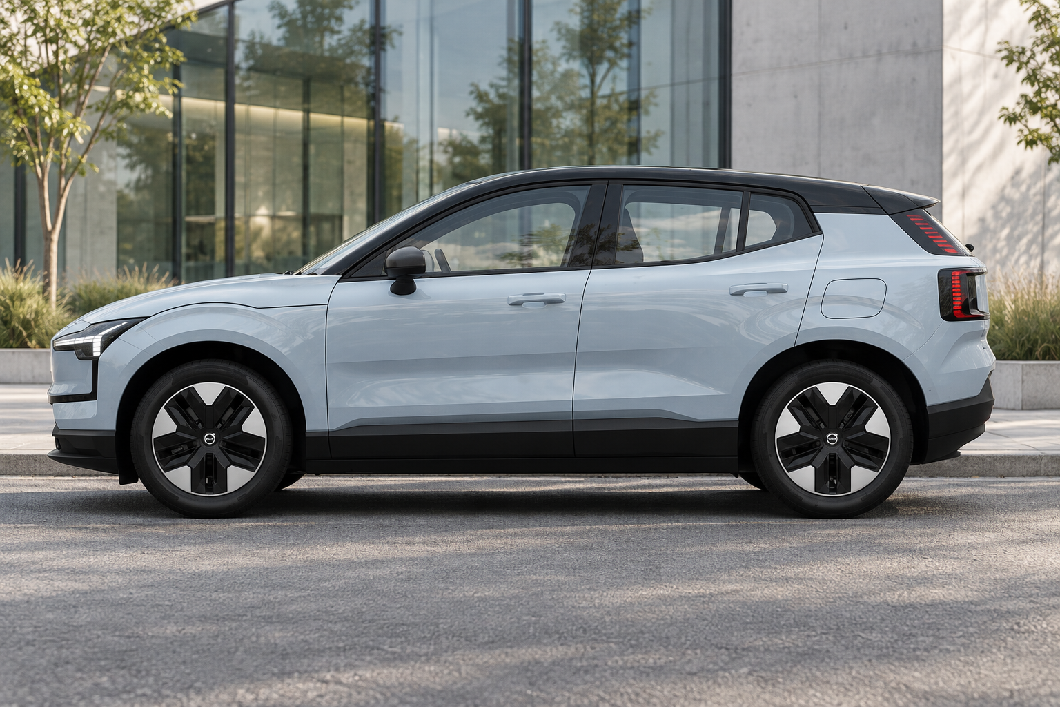 Side view of a Volvo EX30 beside contemporary glass architecture.